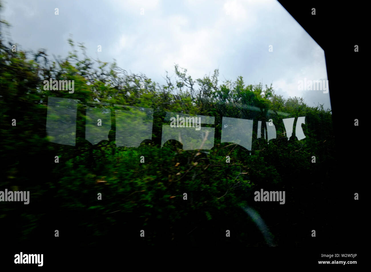 Ansicht aus einem Bus Sitz durch Bus-Fenster auf eine Reflexion der Bus windows und Fahrgäste im Bus in die entgegengesetzte Hecke Stockfoto