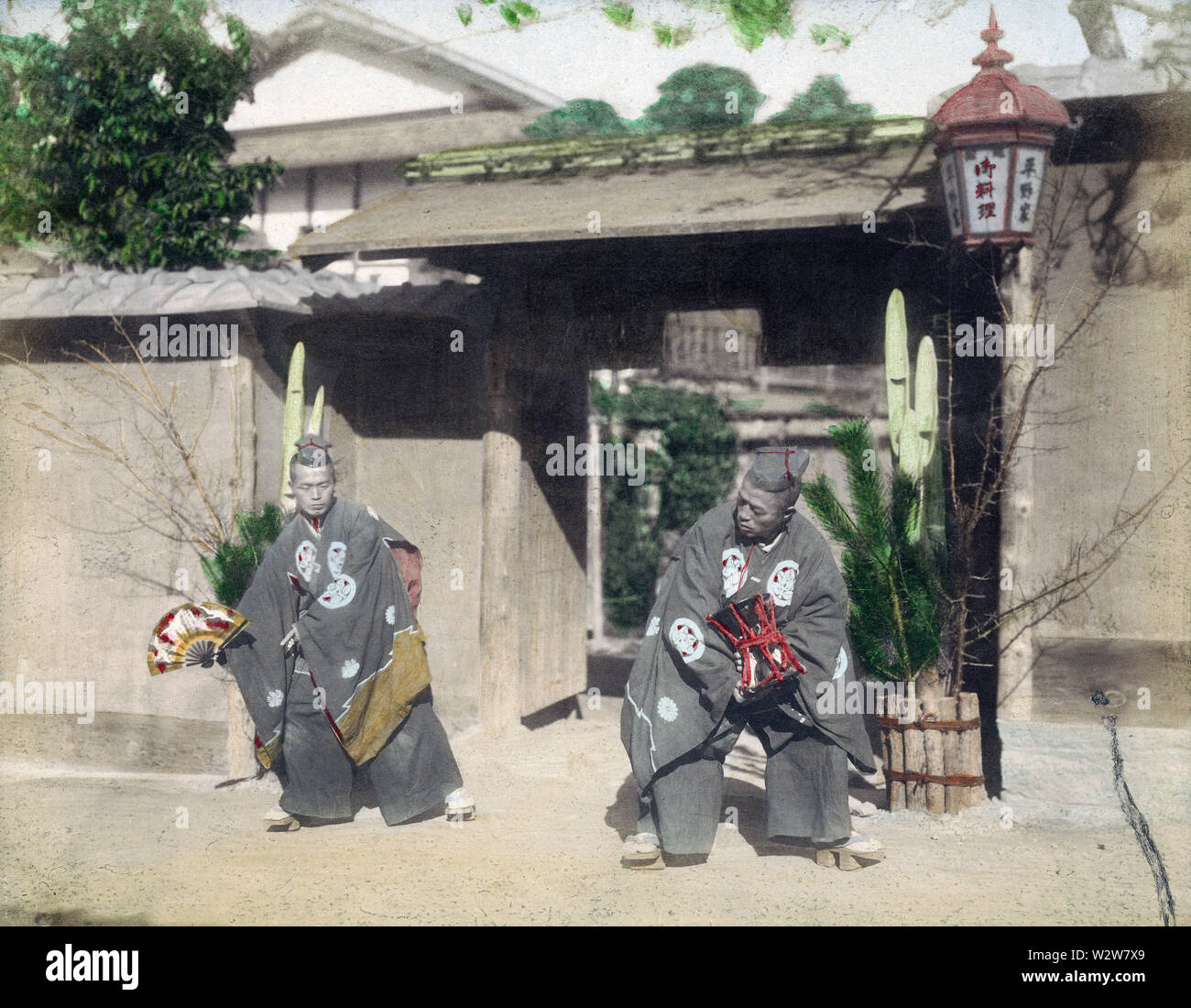 [1890s Japan - Japanische neues Jahr Tanz] - zwei Männer führen einen Tanz vor einem Tor als Teil des neuen Jahres Feiern während der Meiji Periode (1868-1912). 19 Vintage albumen Foto. Stockfoto