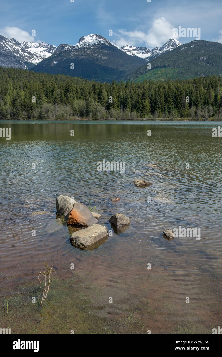Blick über den grünen See von Green Lake Park am Meer entlang zum Sky Highway in der Nähe von Whistler. Schnee sich immer noch zu den höchsten Skipisten des Keils Berg und Stockfoto