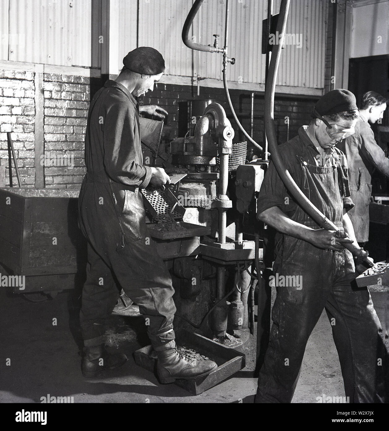 1950, historische, männliche Arbeitnehmer mit industriellen Maschinen Werkzeuge an eine Batterie Fabrik, Walthamstow, London, England, UK. Stockfoto