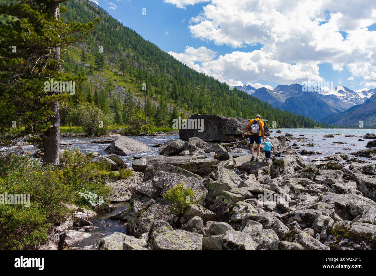Multinsky Seen in Altai Gebirge. Zwei Personen - Vater und Sohn gehen auf den Steinen. Reisen mit Kindern Konzept. Sommer. Stockfoto
