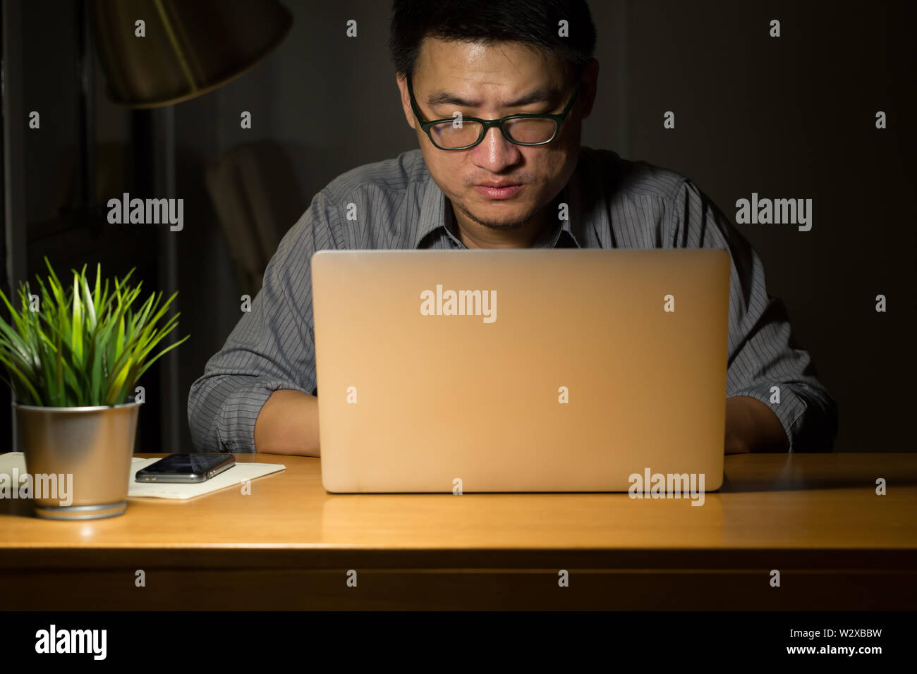 Asian Business Mann nachts arbeiten, freiberuflicher Programmierer oder Entwickler arbeiten zu Hause auf, und geben Sie den Quellcode mit Laptop, Ernst und Überstunden anhand von quantitativen Simulatio Stockfoto