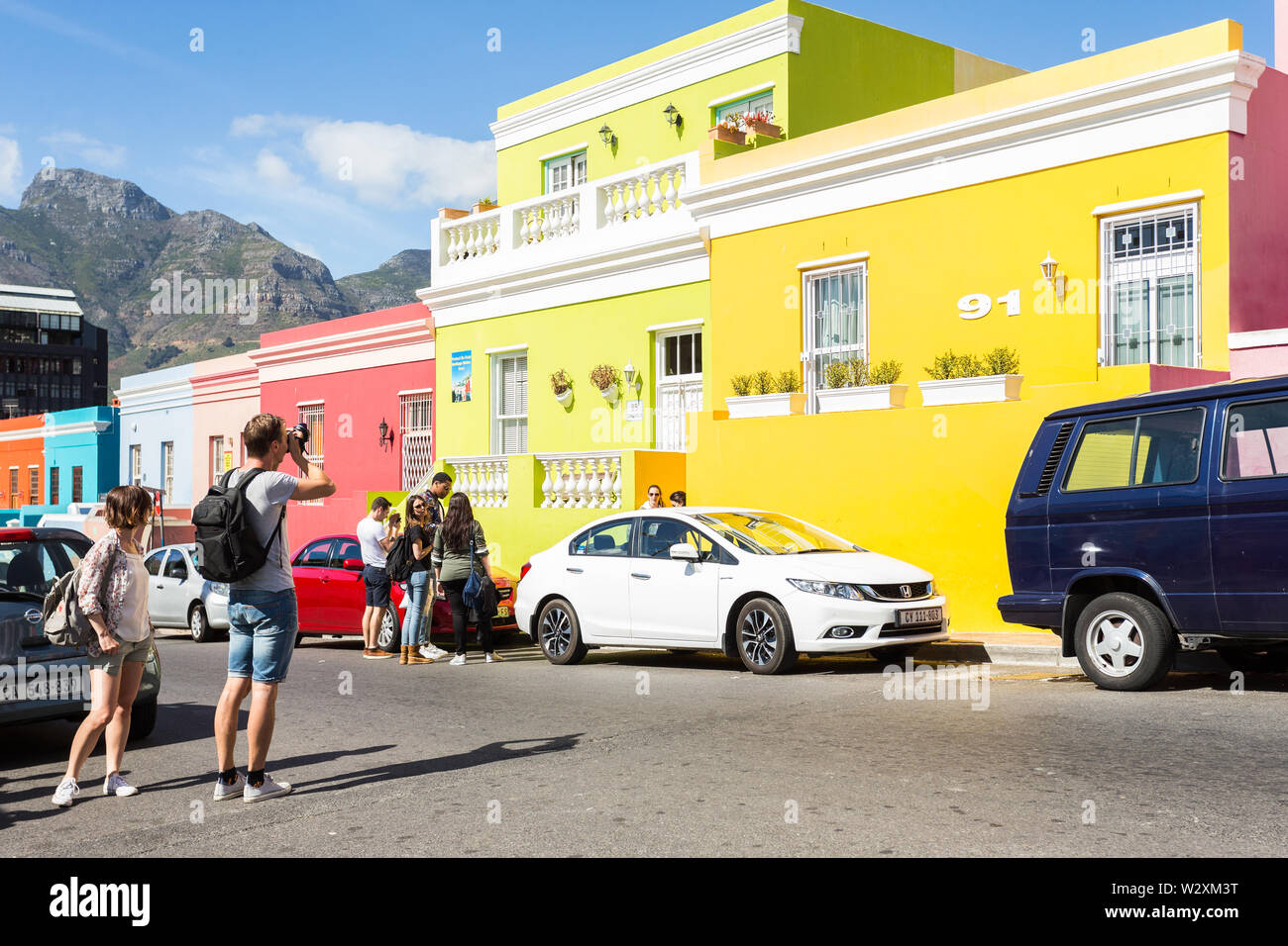 Männliche kaukasischen Tourist, der ein Foto von einer bunten Reihe von Häusern, während in einer Straße in Bo Kaap, Kapstadt, Südafrika während Sightseeing Stockfoto