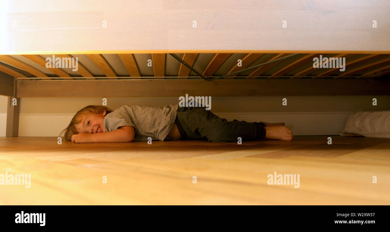 Kind auf der Suche nach etwas unter dem Bett. Stockfoto