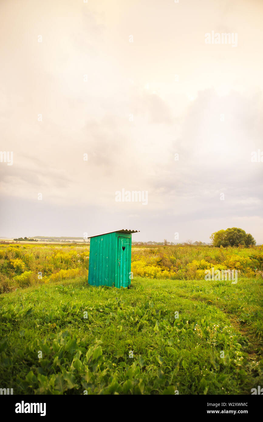 Holz- WC mit einem geschnitzten Fenster in der Form eines Herzens, ein offenes Feld. Stockfoto