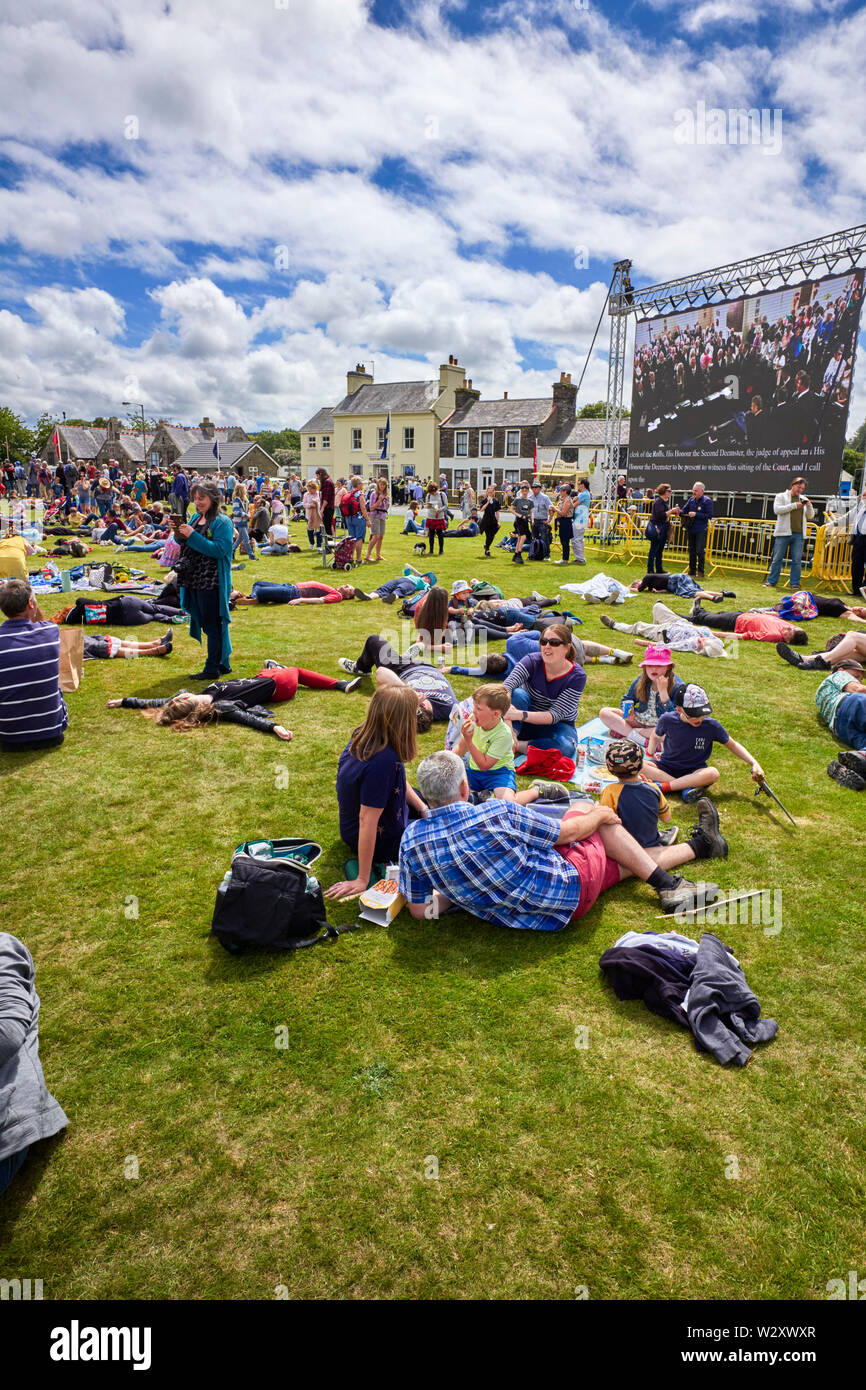 Eine Familie weiterhin mit ihren Picknick während alle um Sie herum Klimawandel Demonstranten legen wie Tot während Tynwald Day 2019 Stockfoto