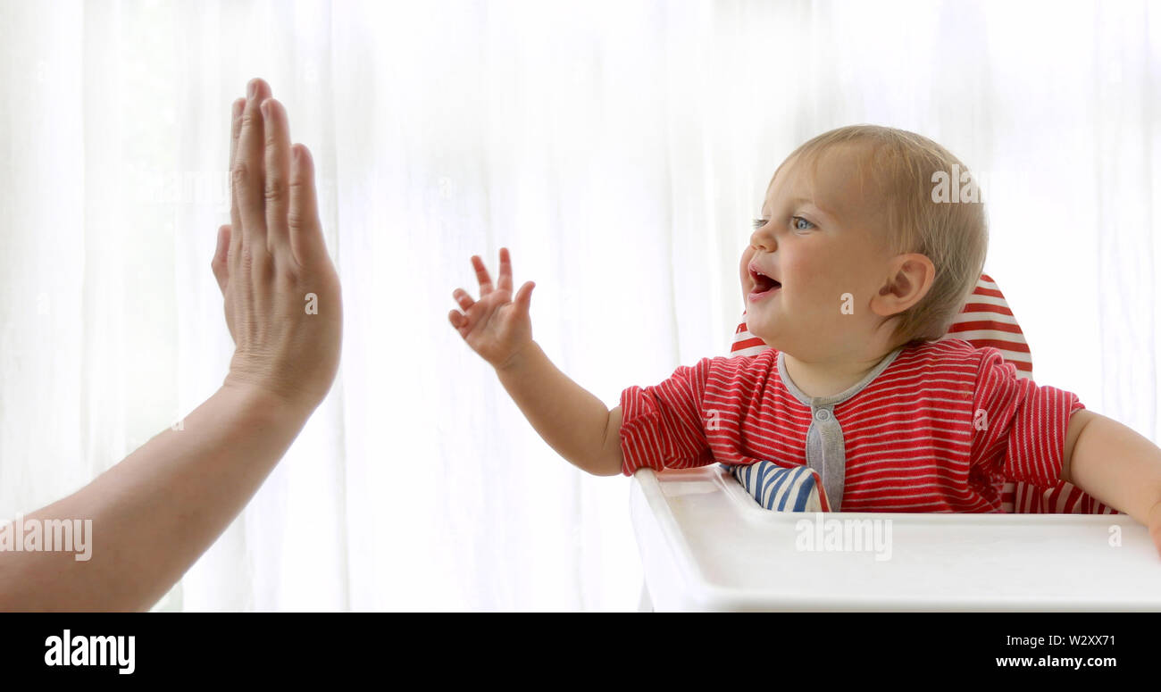 Adorable Happy Baby spielt mit einem Elternteil im Innenbereich Stockfoto