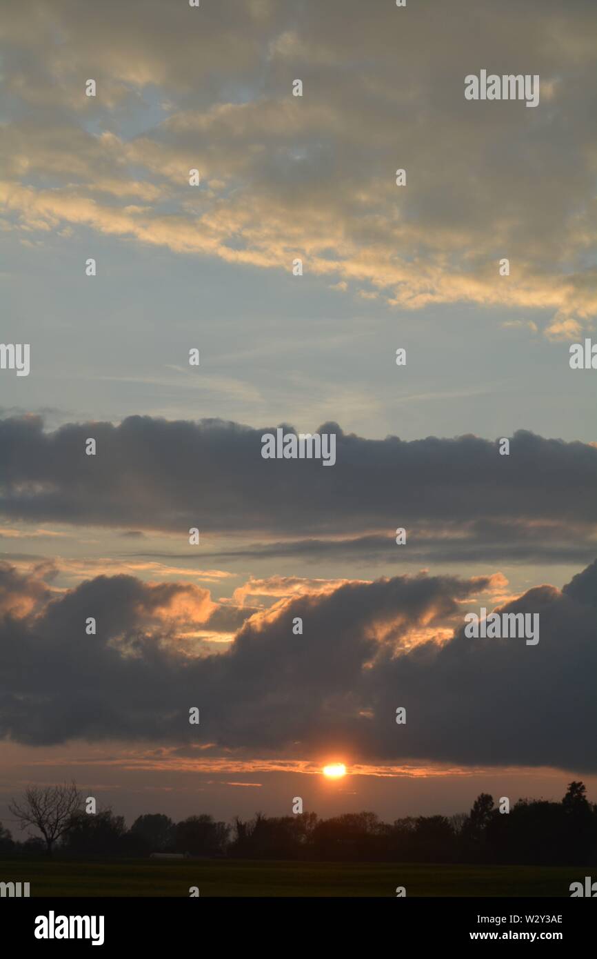 Sequenz von Bildern eines Sonnenuntergangs mit der Sonne erscheinen zwischen Cloud Banken knapp über dem Horizont. Stockfoto