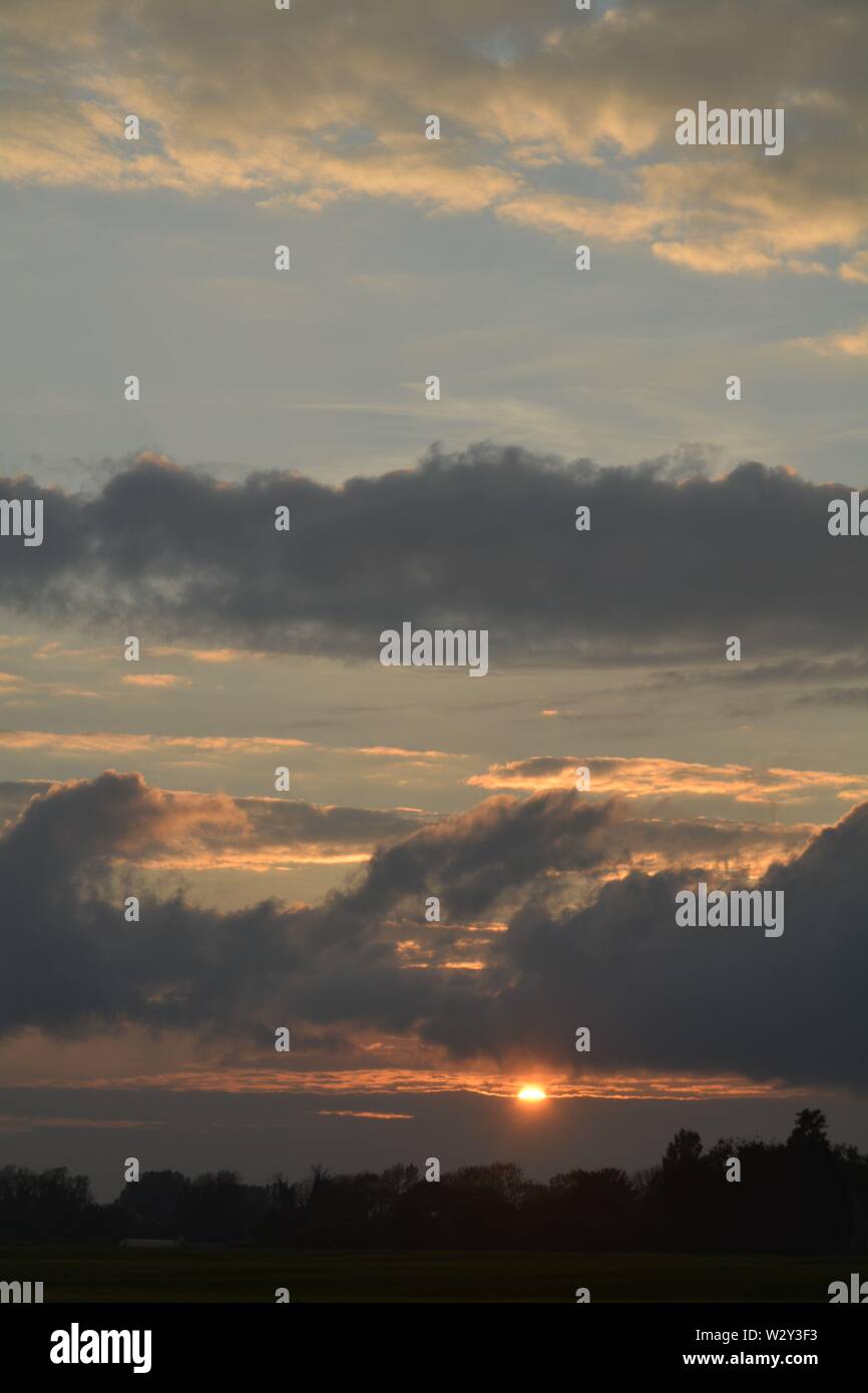 Sequenz von Bildern eines Sonnenuntergangs mit der Sonne erscheinen zwischen Cloud Banken knapp über dem Horizont. Stockfoto