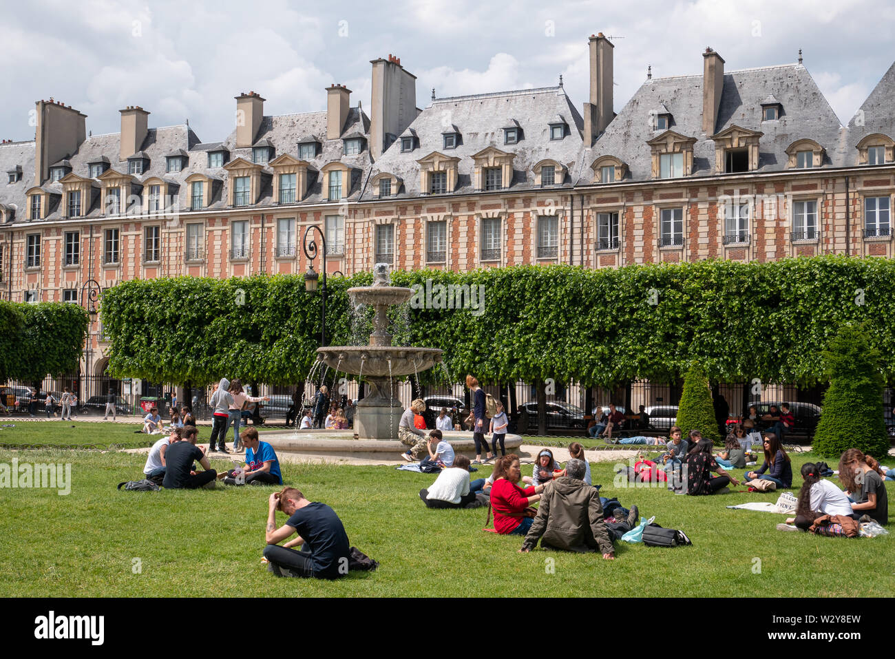Paris, Frankreich, 25. Mai 2019: Place des Vosges. Menschen entspannend auf den grünen Rasen der berühmten Place des Vosges - älteste geplante Platz im Viertel Marais. Stockfoto