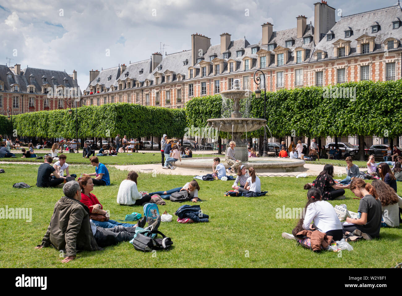 Paris, Frankreich, 25. Mai 2019: Place des Vosges. Menschen entspannend auf den grünen Rasen der berühmten Place des Vosges - älteste geplante Platz im Viertel Marais. Stockfoto