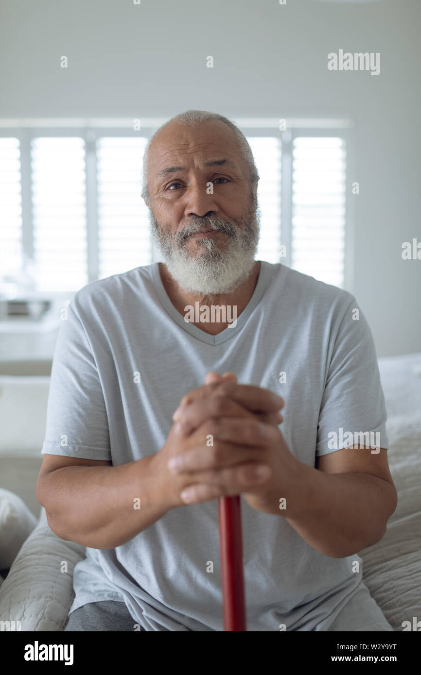 Mann sitzt auf dem Bett, während Sie eine hölzerne Spazierstock Stockfoto