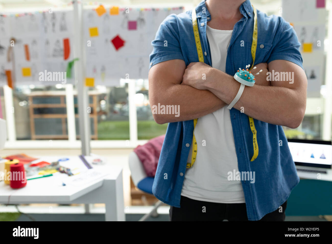 Männliche Fashion Designer Sitzen mit gekreuzten Armen im Design Studio Stockfoto