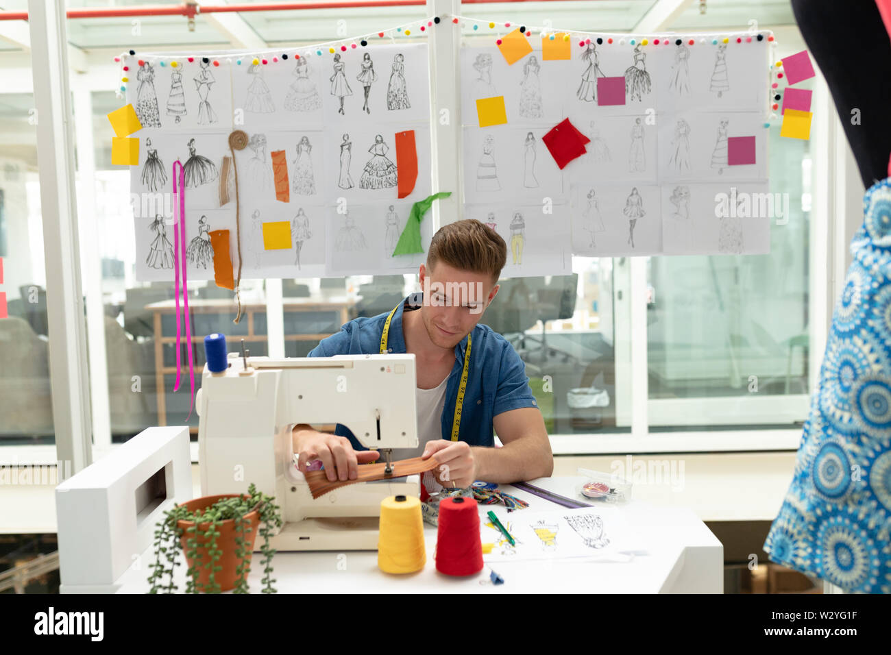 Männliche Modedesigner mit Nähmaschine auf einem Tisch Stockfoto