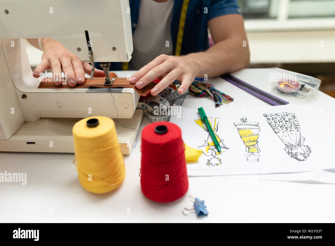 Männliche Modedesigner mit Nähmaschine auf einem Tisch im Design Studio Stockfoto