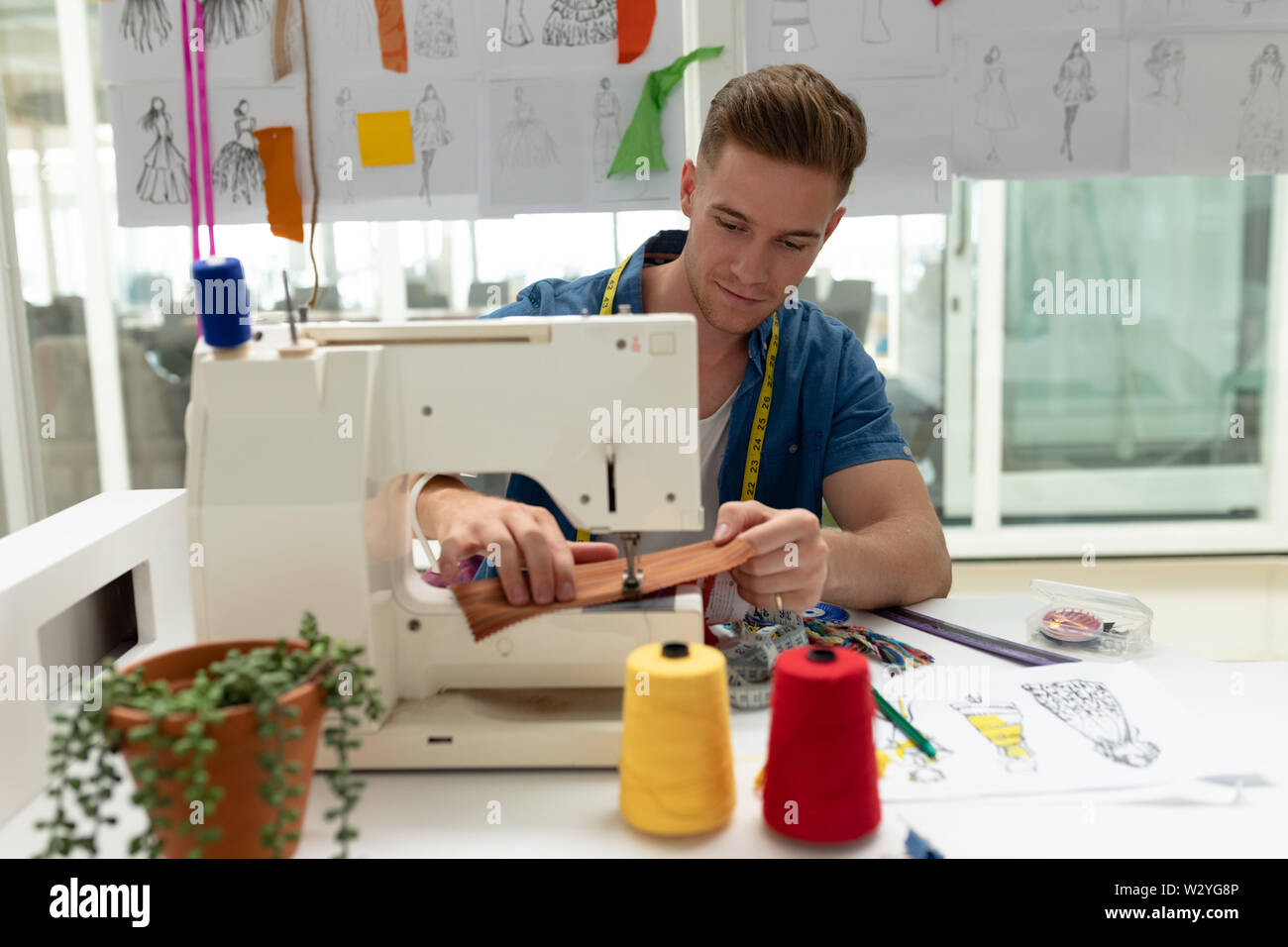 Männliche Modedesigner mit Nähmaschine auf einem Tisch Stockfoto