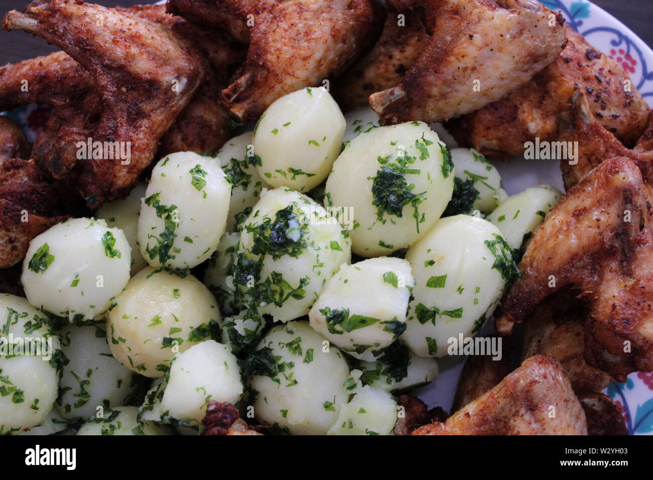 Crunchy Chicken Wings mit Baby Kartoffeln und Petersilie Stockfoto