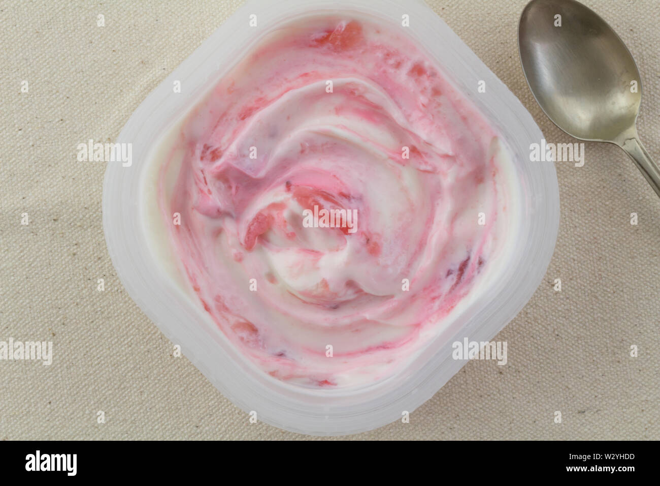 Joghurtbecher mit natürlichen Erdbeere griechische weiss und rosa Joghurt wirbelte mit echten Erdbeeren auf rustikalen Bettwäsche Hintergrund isoliert mit kleinen, silber s Stockfoto