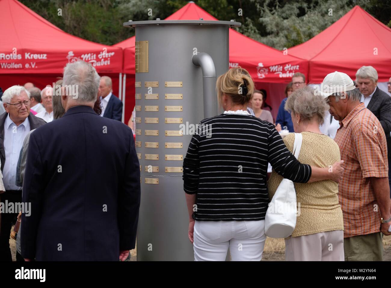 Bitterfeld Wolfen, Deutschland. 11. Juli, 2019. Die Teilnehmer der Gedenkfeier stehen an einem Denkmal in der Chemischen Park. Eine Stele erinnert an die Opfer der chemischen Unfall vom 11.07.1968, bei der 40 Menschen starben und mehr als 240 wurden verletzt. Credit: Sebastian Willnow/dpa-Zentralbild/dpa/Alamy leben Nachrichten Stockfoto