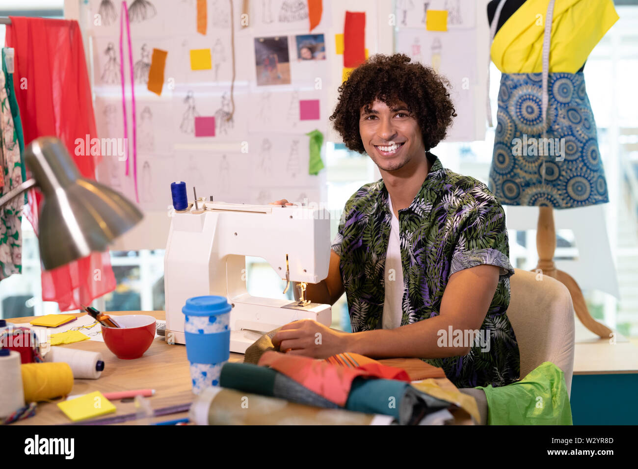 Männliche Modedesigner mit Nähmaschine auf einem Tisch im Design Studio Stockfoto