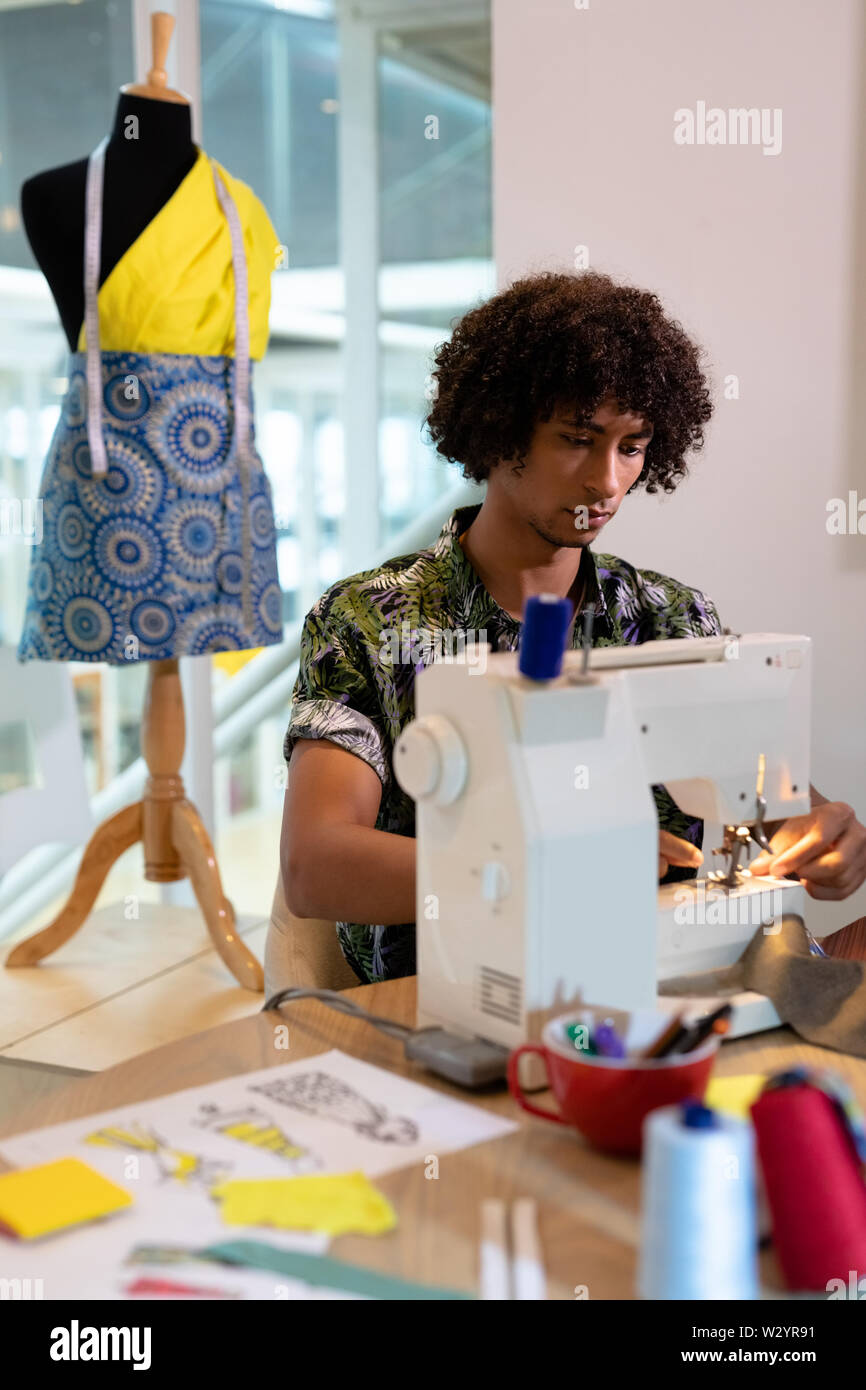 Männliche Modedesigner mit Nähmaschine auf einem Tisch Stockfoto