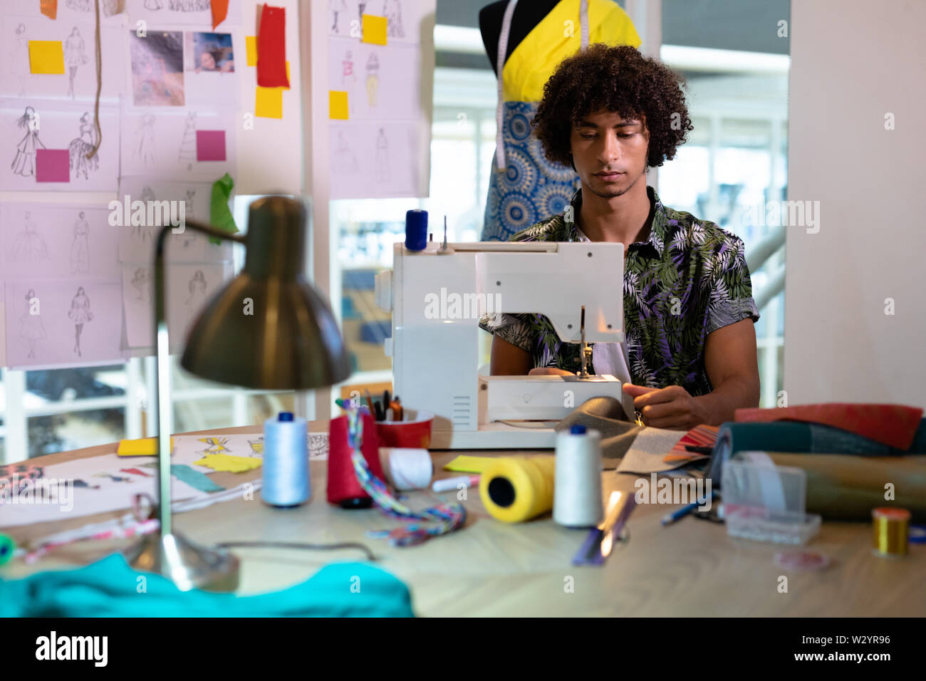 Männliche Modedesigner mit Nähmaschine auf einem Tisch Stockfoto