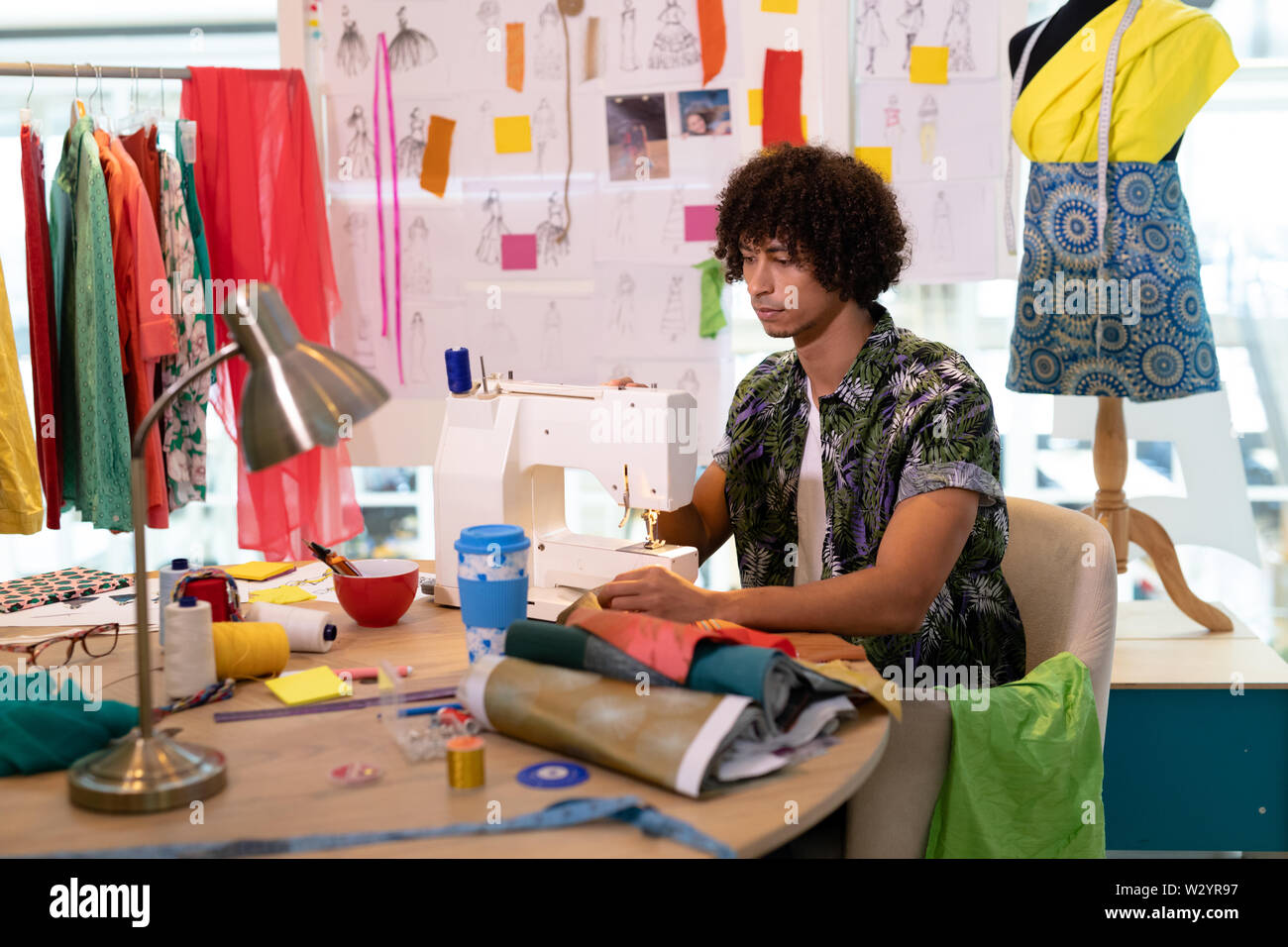 Männliche Modedesigner mit Nähmaschine auf einem Tisch Stockfoto