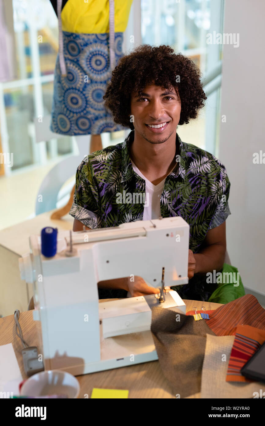 Männliche Modedesigner mit Nähmaschine auf einem Tisch im Design Studio Stockfoto