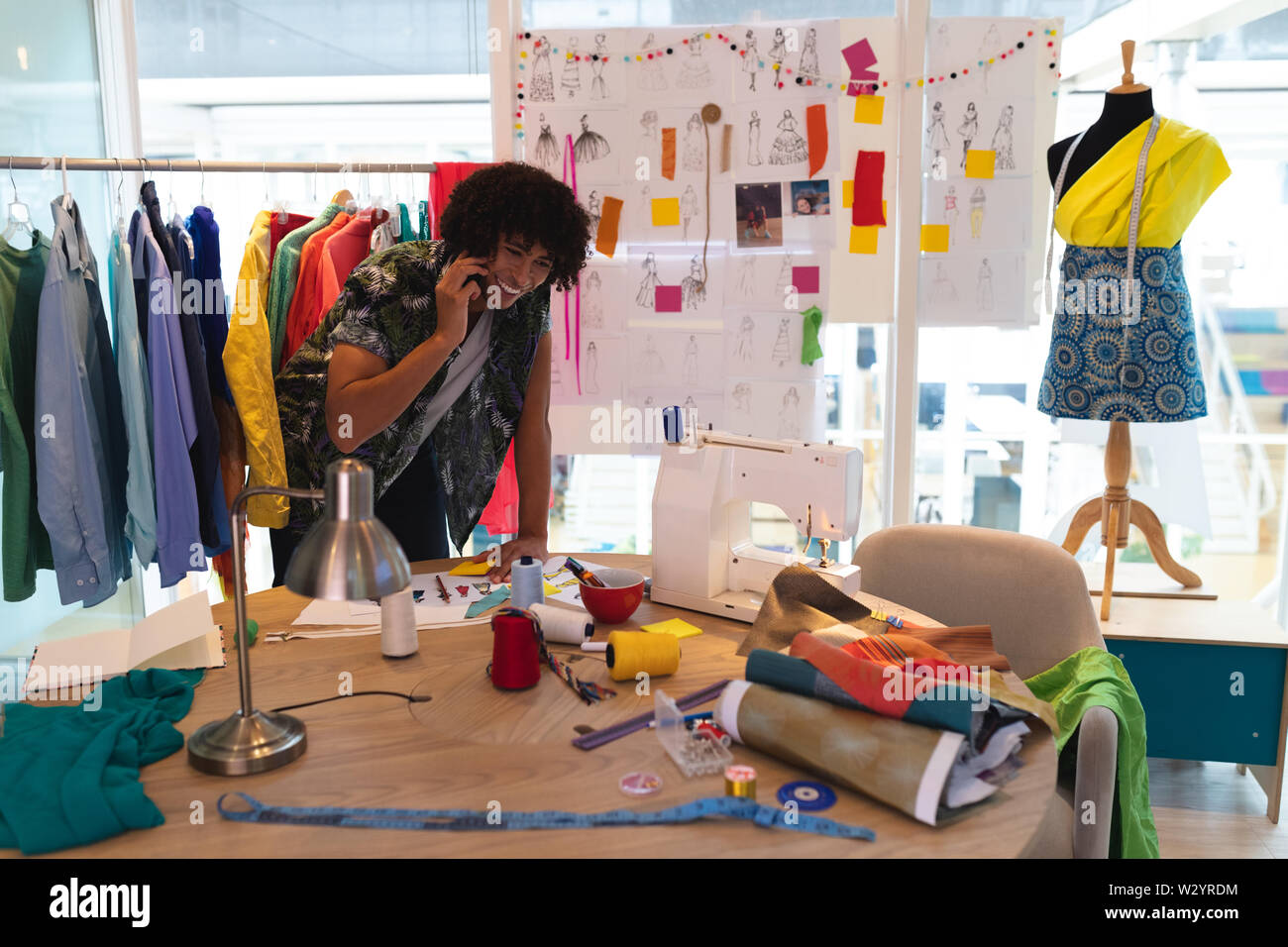 Männliche Fashion Designer Gespräch am Handy während der Arbeit auf einem Tisch Stockfoto