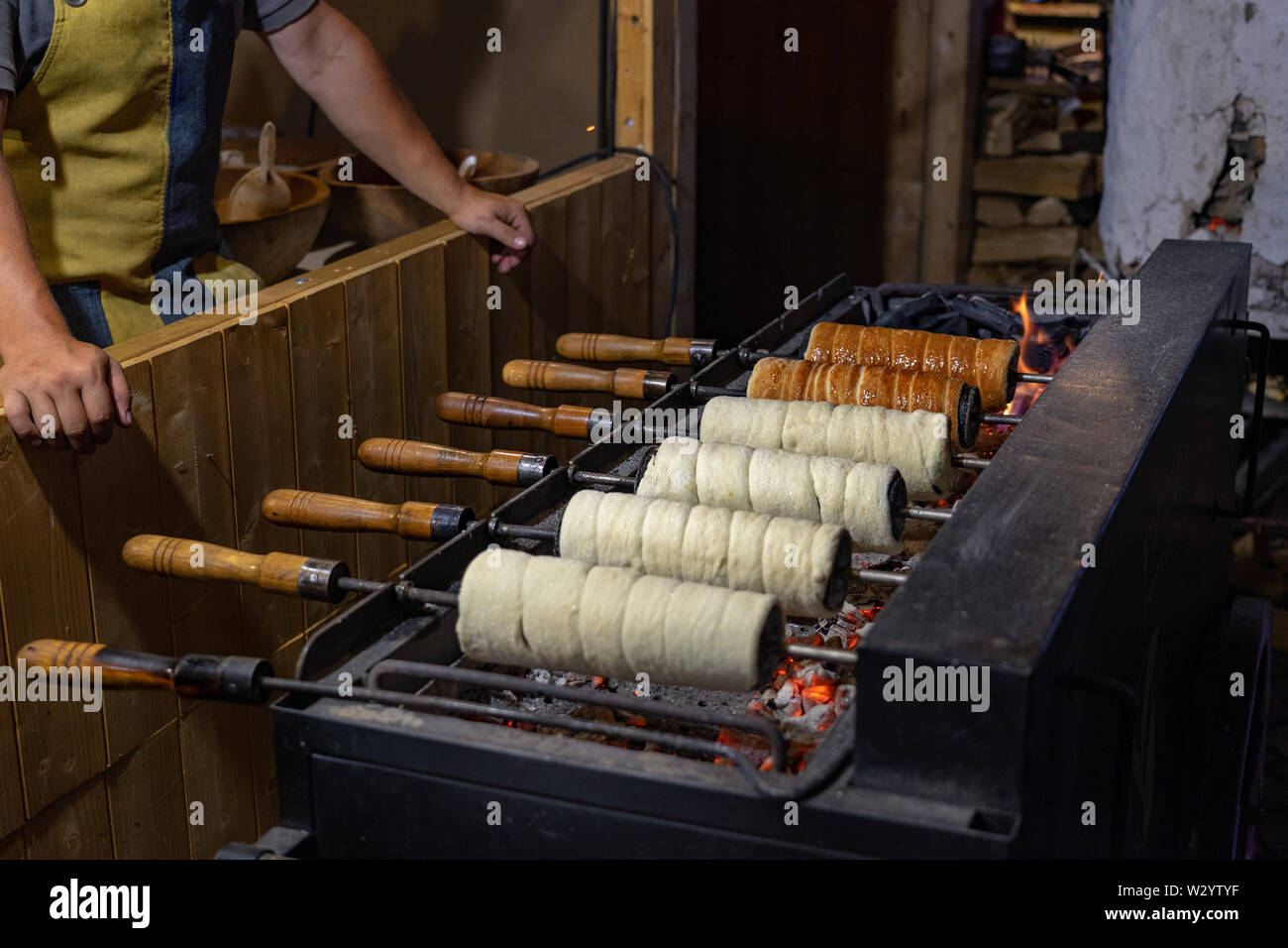 Ein Schornstein Kuchen wird über einem offenen Holzkohlegrill gebacken. Stockfoto