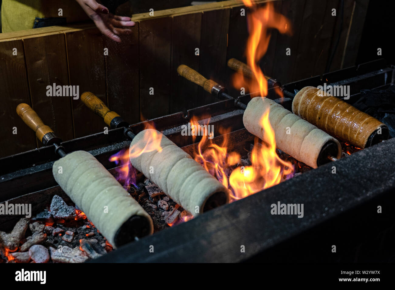 Ein Schornstein Kuchen wird über einem offenen Holzkohlegrill gebacken. Stockfoto