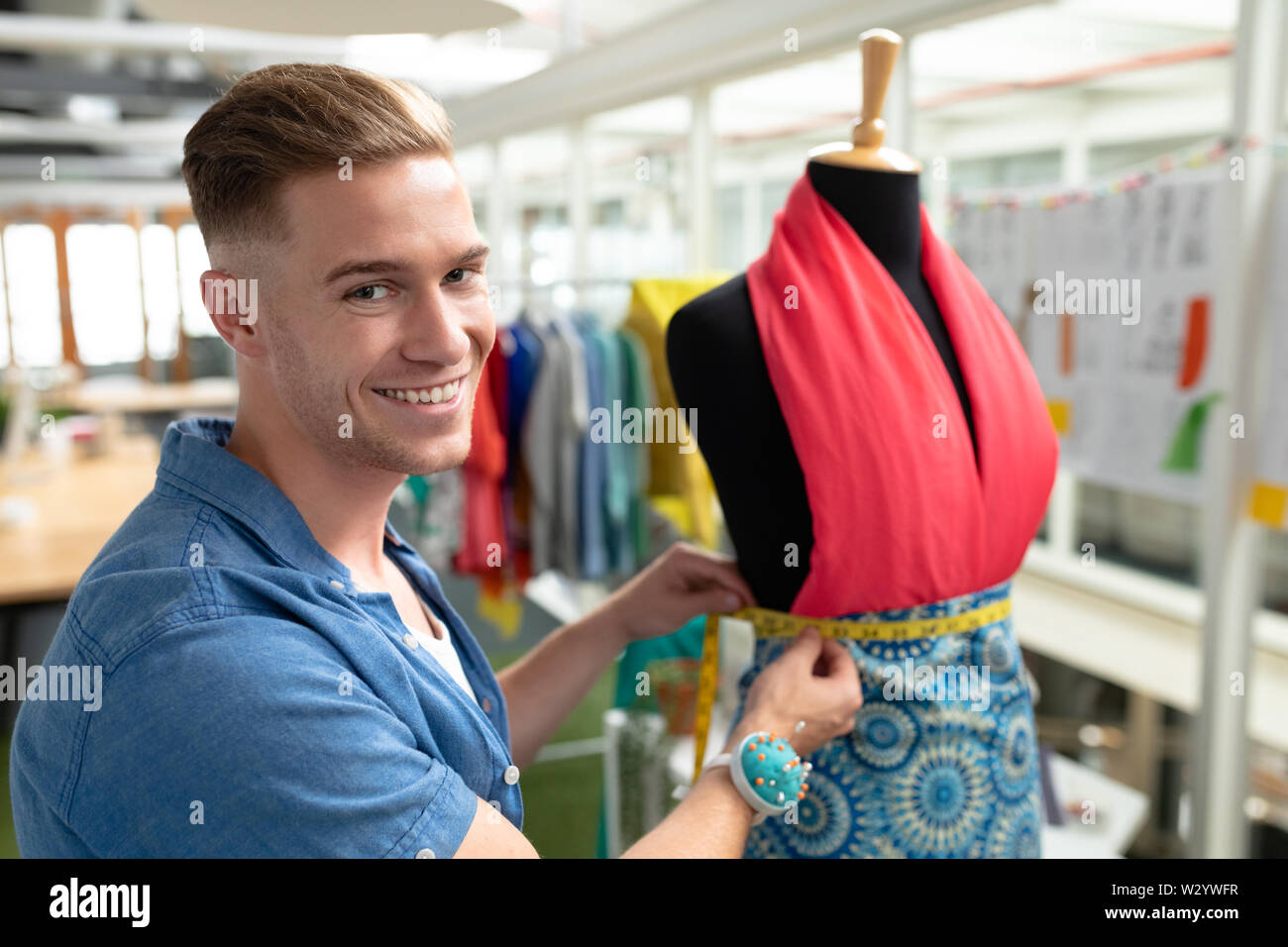 Männliche Modedesigner mit Maßband auf eine Schaufensterpuppe in Design Studio Stockfoto