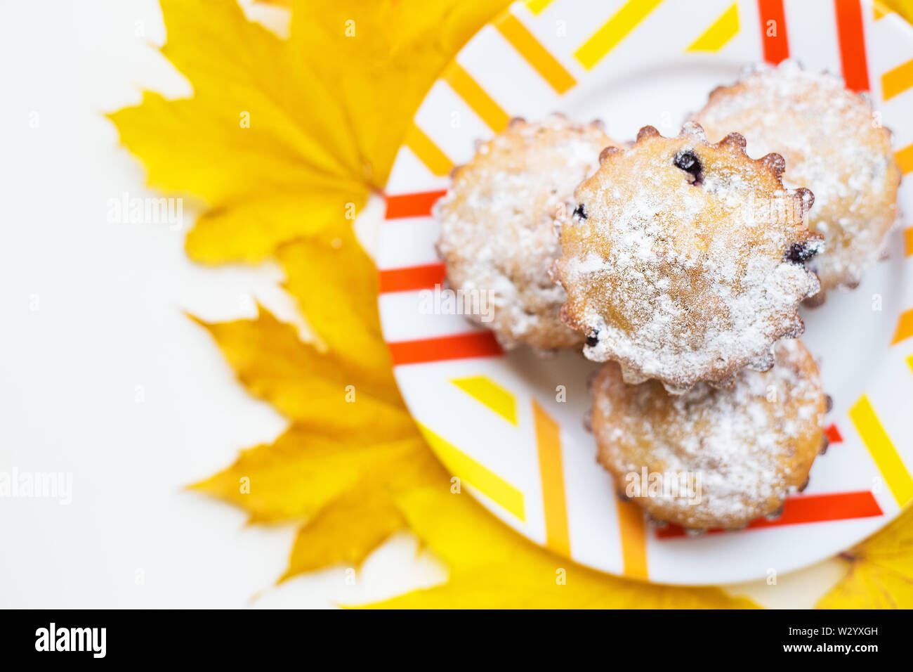 Farbige Cupcakes auf einer Platte und gelben Blätter im Herbst, close-up Stockfoto
