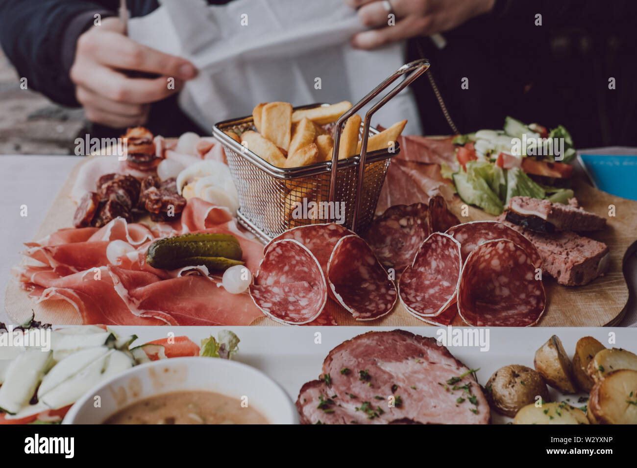 Nahaufnahme der männlichen Hände halten eine Gabel, essen Aufschnitt platter mit Chips, selektive konzentrieren. Stockfoto