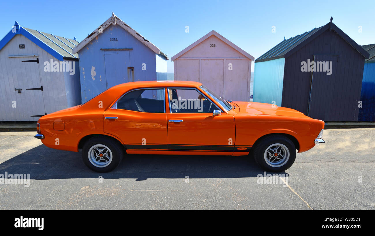 Classic Orange Ford Cortina Mk3 Auto geparkt am Strand Hütten. Stockfoto