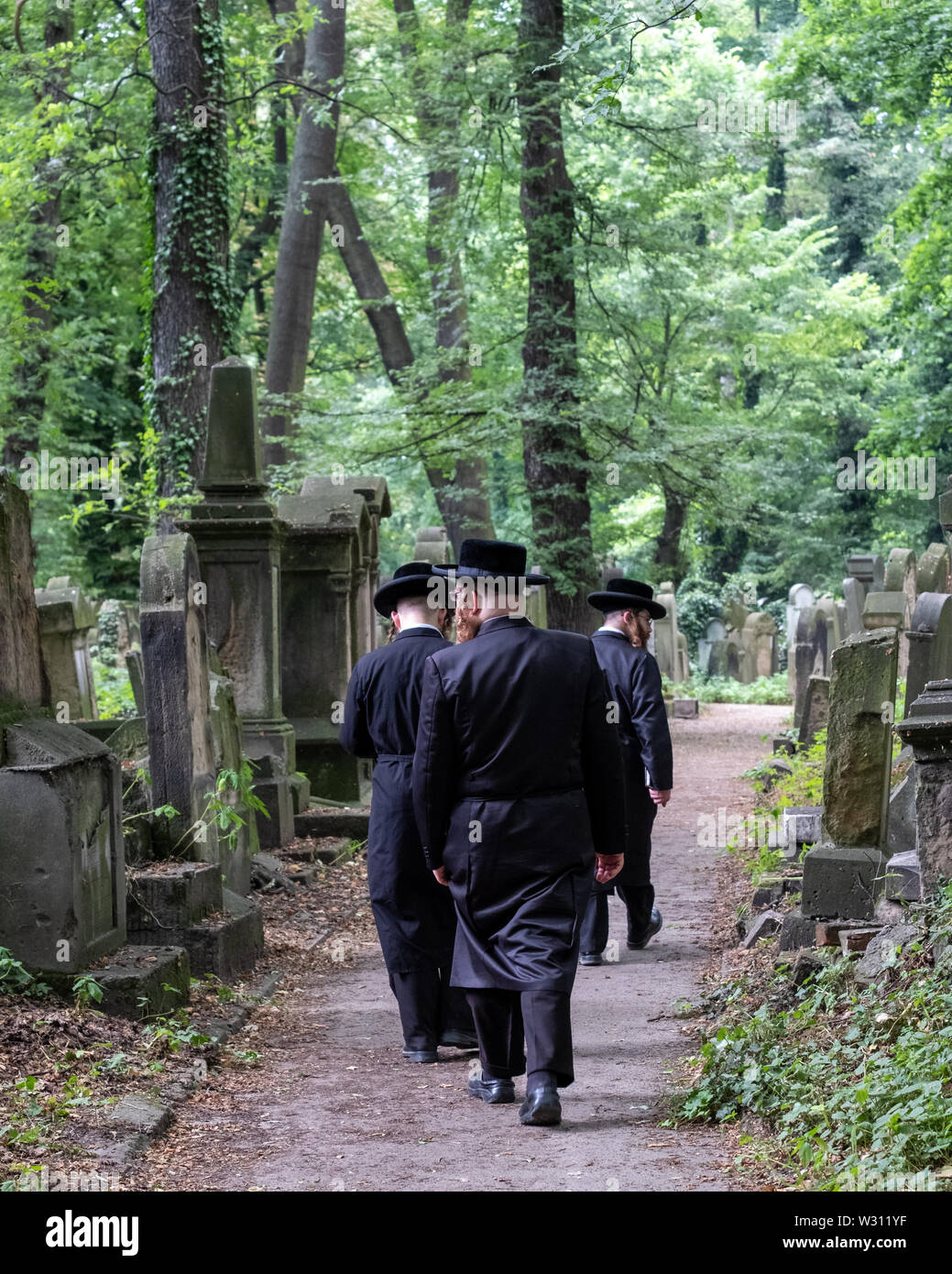 Jüdische Chasidic Männer in traditionellen lange schwarze Mäntel und Hüte Spaziergang durch die alten Grabsteine in der Neuen Jüdischen Friedhof in Kazimierz in Krakau, Polen Stockfoto