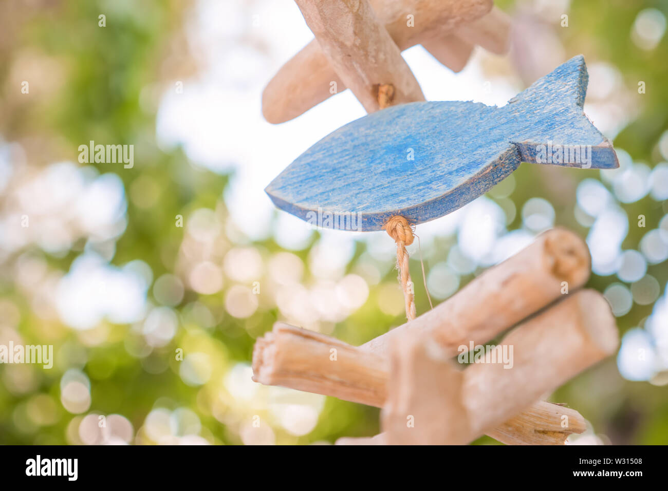 Holz- Fisch mit Park im Hintergrund. Aushängeschild einer Fischtaverne, Cafe, Restaurant mit Fisch essen. Holz- Fisch als Zeichen des Glaubens. Fisch Zeichen und Symbol Stockfoto