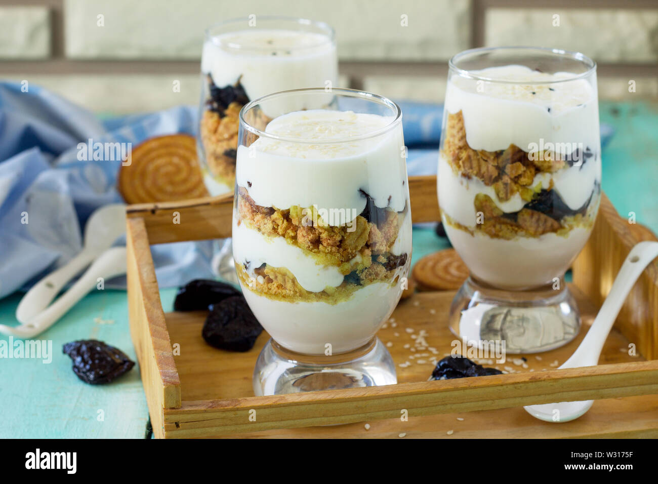 Veganes Dessert mit Schlagsahne, Nüssen, Haferflocken, Pflaumen und Sesam in Glas Gläser auf einer hölzernen rustikalen Tisch. Stockfoto