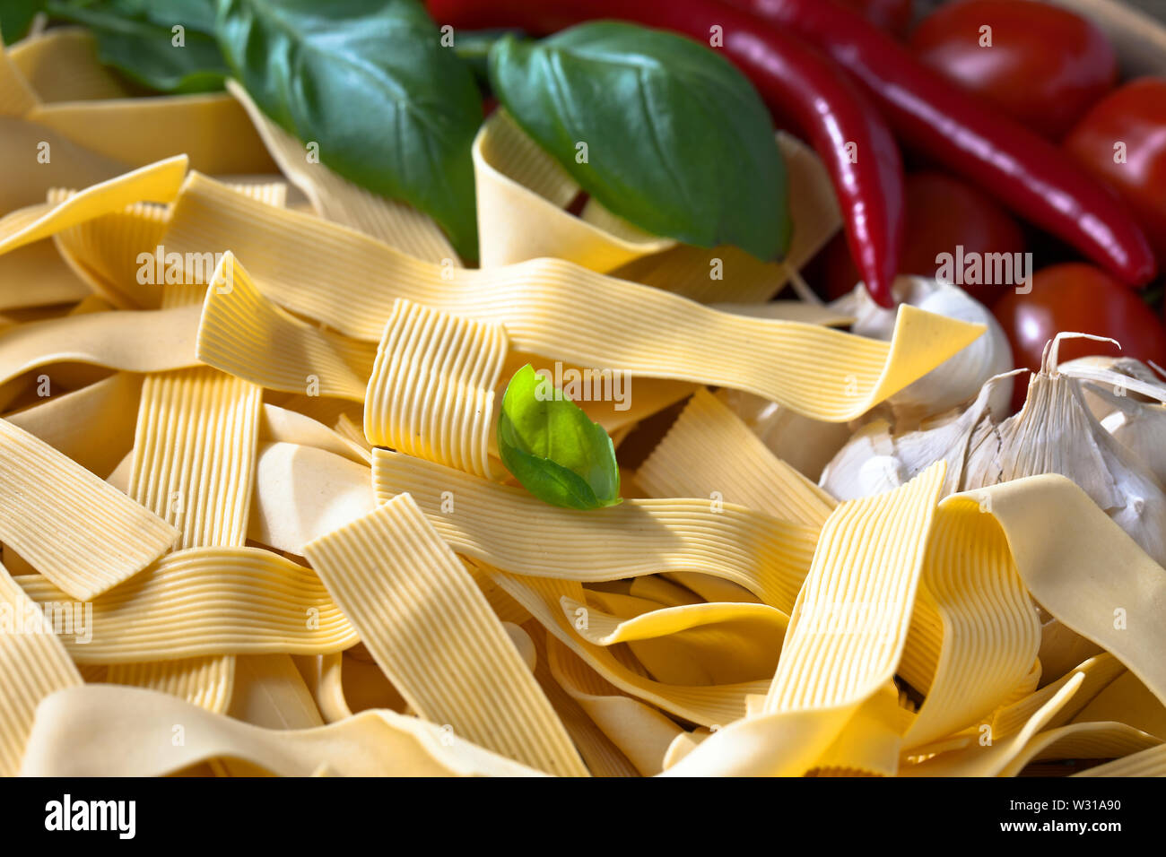 Ungekochte Nudeln mit Basilikum, Knoblauch, Pfeffer, Chili und Tomaten. Italienische Küche. Stockfoto