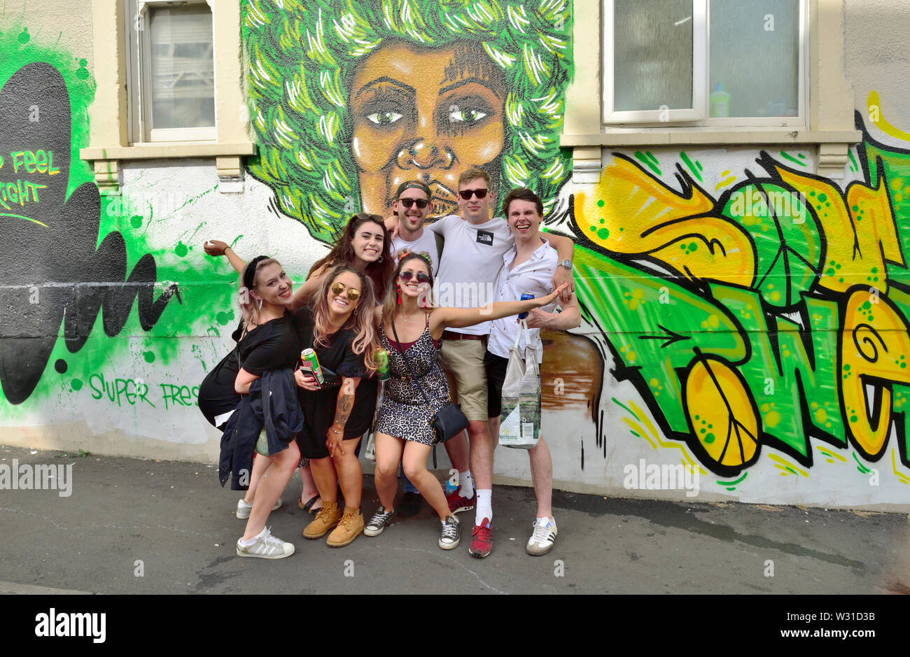 Gruppe junger Freunde posiert von Wand mit Graffiti Kunst während Bristol St Paul's Karneval Stockfoto
