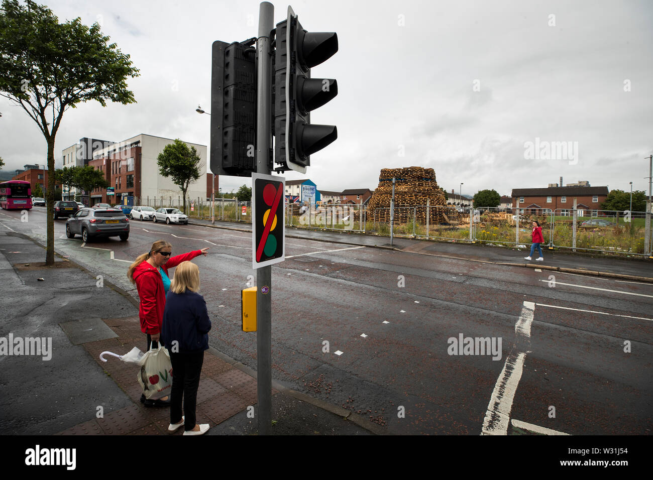 Eine Frau weist auf die fehlende Ampel auf der Fußgängerampel auf der Shankill Road in Belfast, an der Kreuzung mit der Boundary Street, die jährlich rund 11 Juli ausgebaut ist, um jegliche Schäden, die durch die Nähe der nahegelegenen 11. Nacht Lagerfeuer zu verhindern. Das Signal Köpfe sind wieder errichtet, so bald wie möglich nach dem Ereignis, mit Fußgängern geraten, die nächste alternative Crossing in der Craven Street zu verwenden Stockfoto