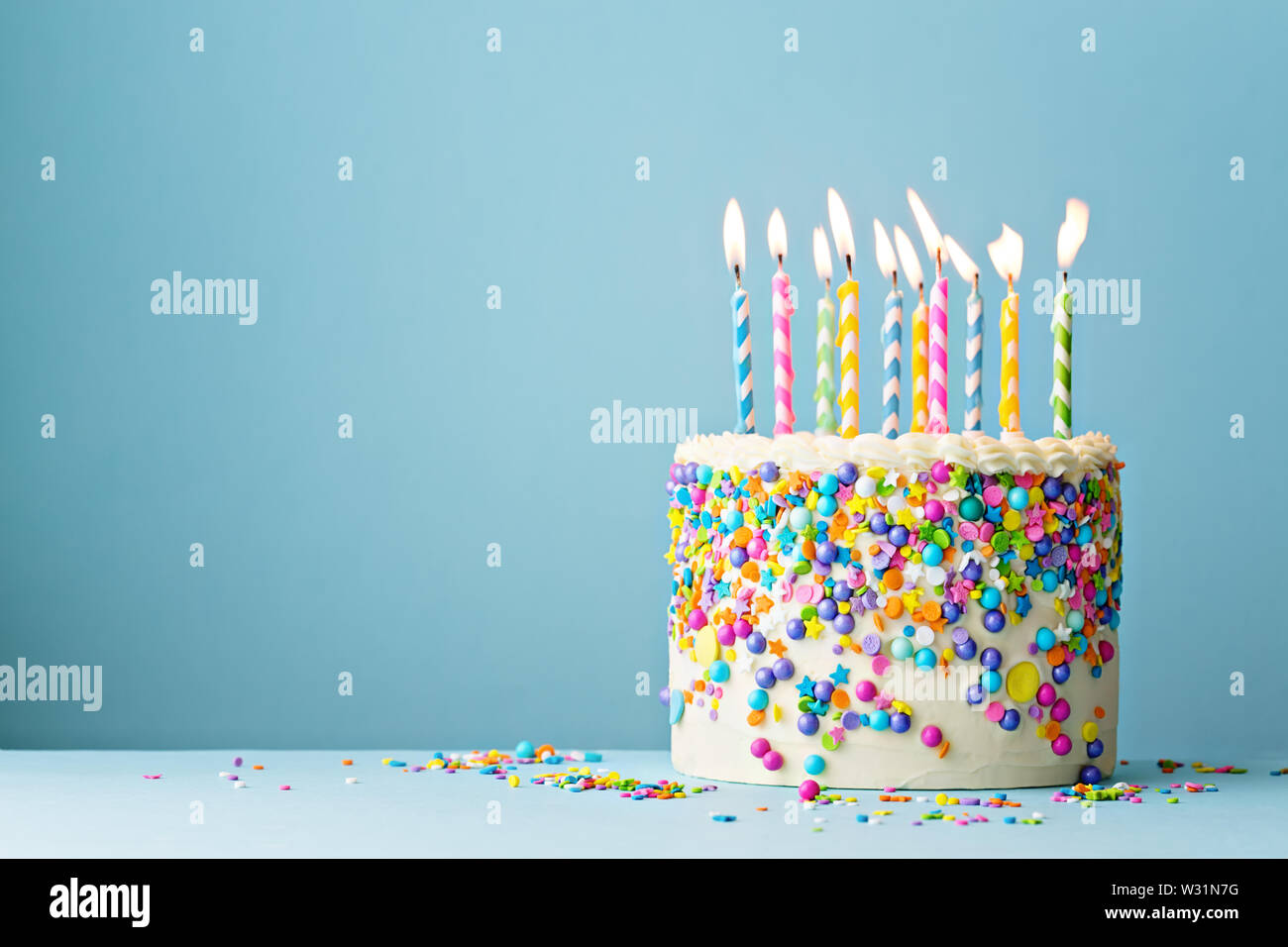 Bunte Geburtstag Kuchen mit Streuseln und zehn Kerzen auf einem blauen Hintergrund mit Copyspace Stockfoto