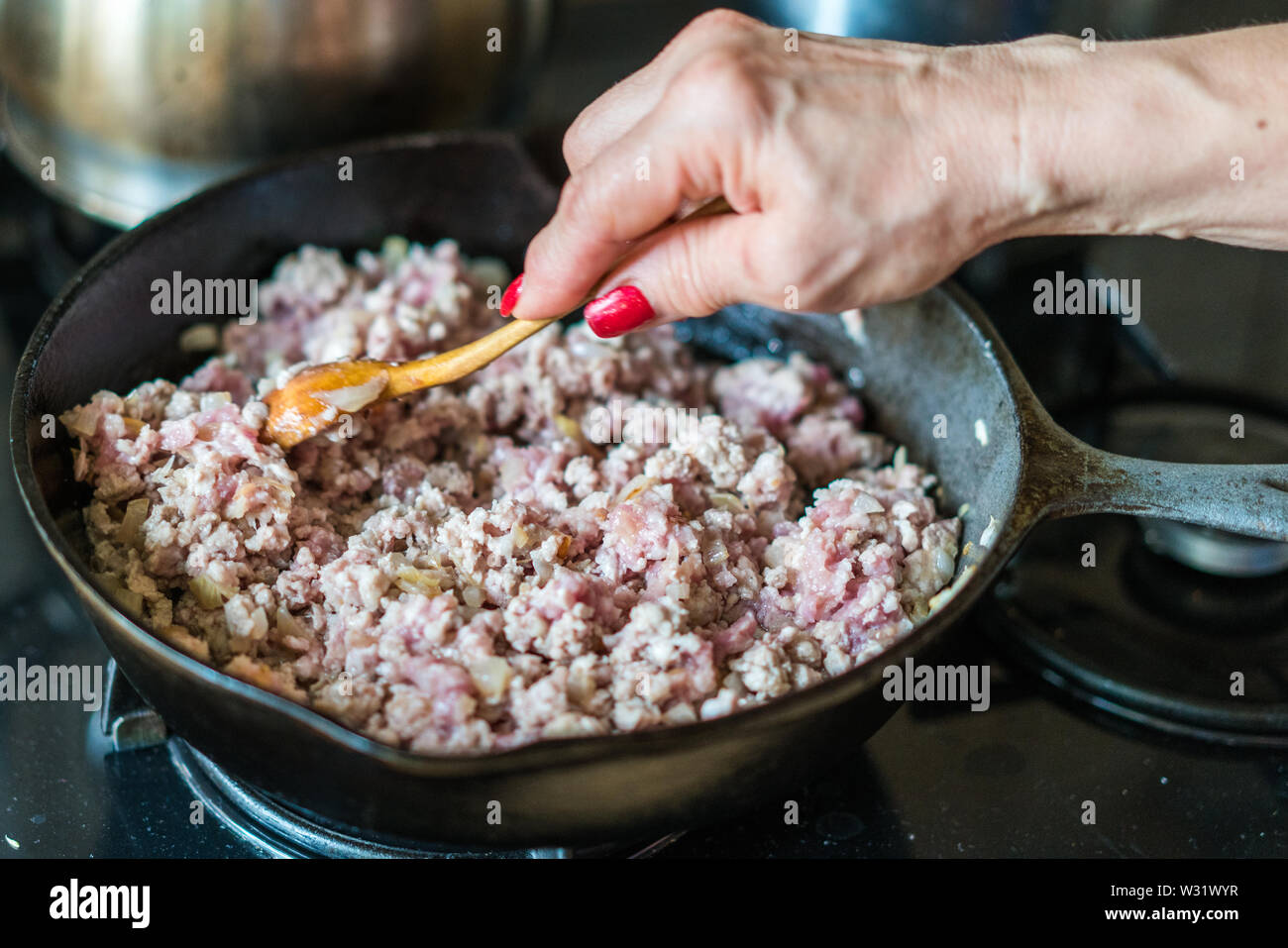 Frau rühren Boden Schweinefleisch gebraten auf einer Pfanne Stockfoto