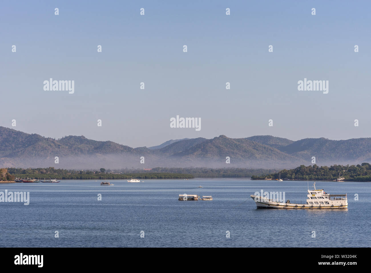 Puerto Princesa, Palawan, Philippinen - 3. März 2019: Die Bucht vor der Stadt zeigt, blaues Wasser und braune Berge bedeckt in einem leichten Dunst in der Stockfoto