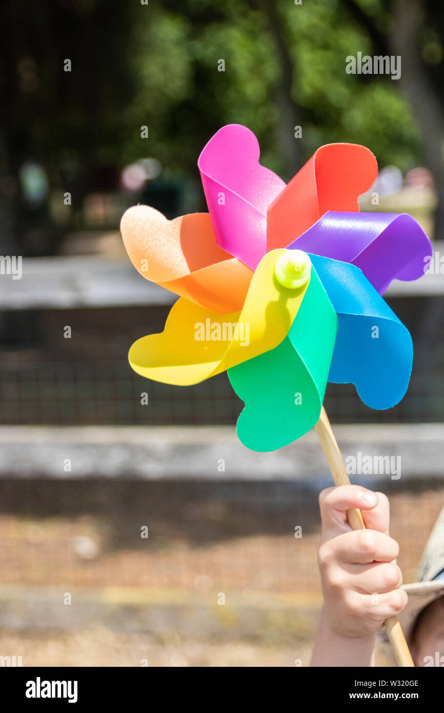 Eine hand Halten eines childs milti farbigen Regenbogen Mühle Stockfoto