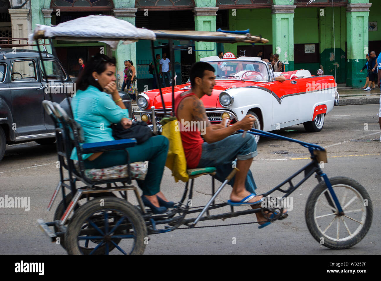 Havanna - Kuba/16. Oktober 2011, kubanische Frau ist mit der Rikscha, die in Bewegung ist mit einem klassischen Kubanischen Auto im Hintergrund Reisen Stockfoto