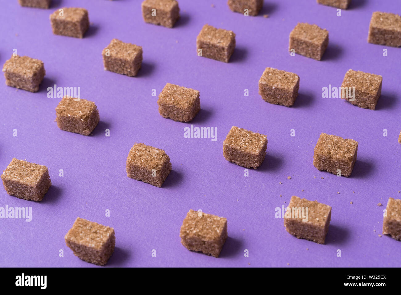 Blick von oben auf die Brown Sugar cubes gegen lila Hintergrund. Minimalismus Stil. Stockfoto