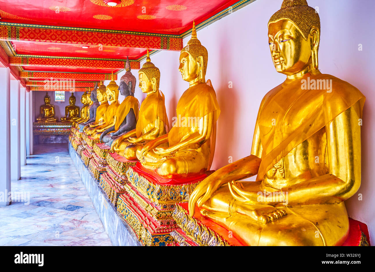 BANGKOK, THAILAND - 22. APRIL 2019: Die Linie der goldenen Statuen des Buddha in überdachten Galerie von Phra Rabiang Kloster Wat Pho temle, am 2. April Stockfoto