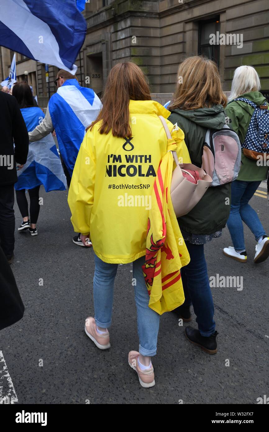 Eine junge Frau in einem gelben Scottish National Party Jacke mit 'Ich bin mit Nicola', die auf der Rückseite während eine Unabhängigkeit März in Glasgow, Schottland, Großbritannien Stockfoto
