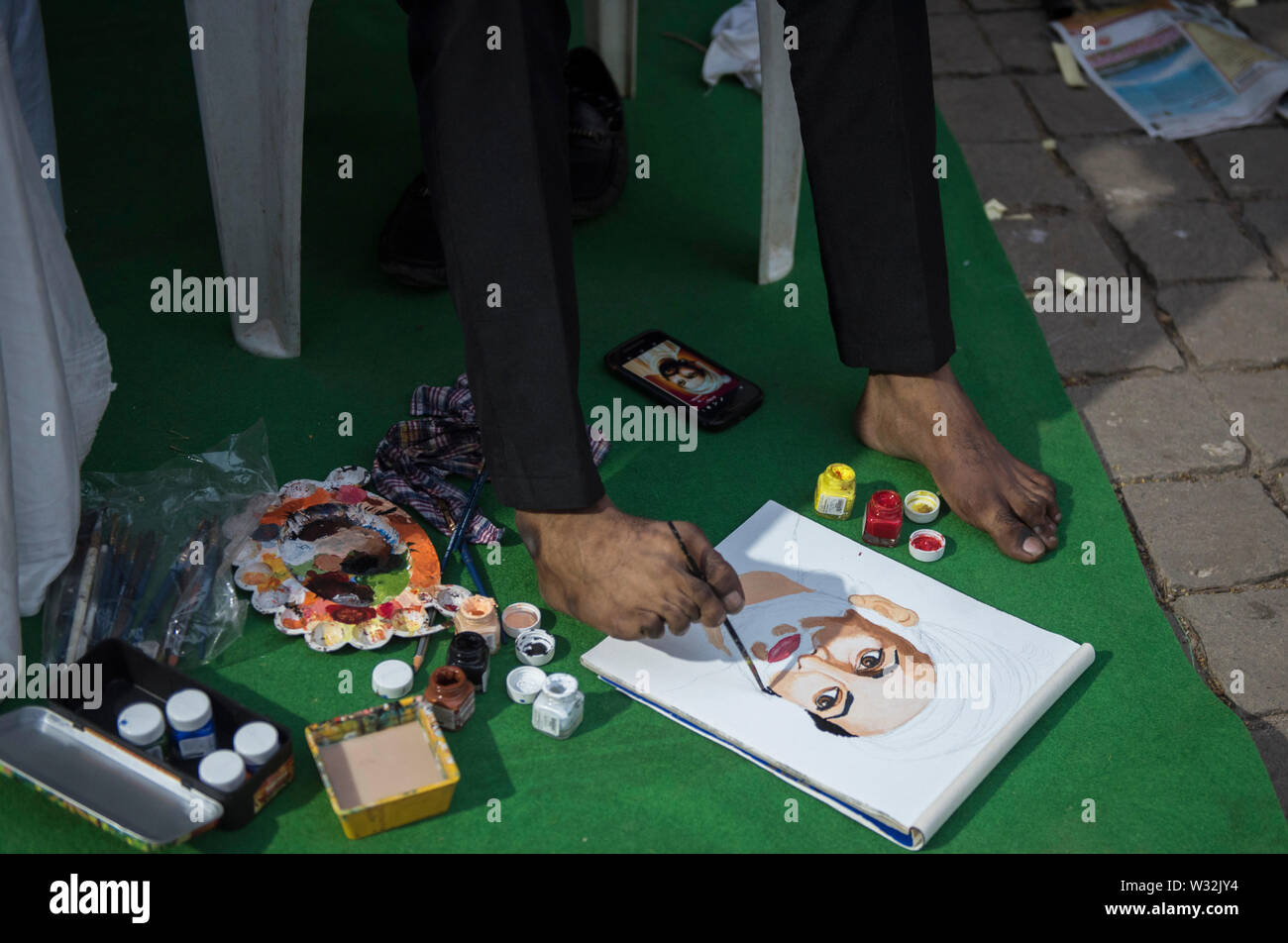 Eine körperlich behinderte Mann malt mit seinem Bein in Mumbai, Indien Stockfoto